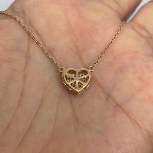 Puede incluir: Un collar de oro con un colgante en forma de coraz&oacute;n y una cadena delicada. El colgante est&aacute; adornado con peque&ntilde;as piedras brillantes.