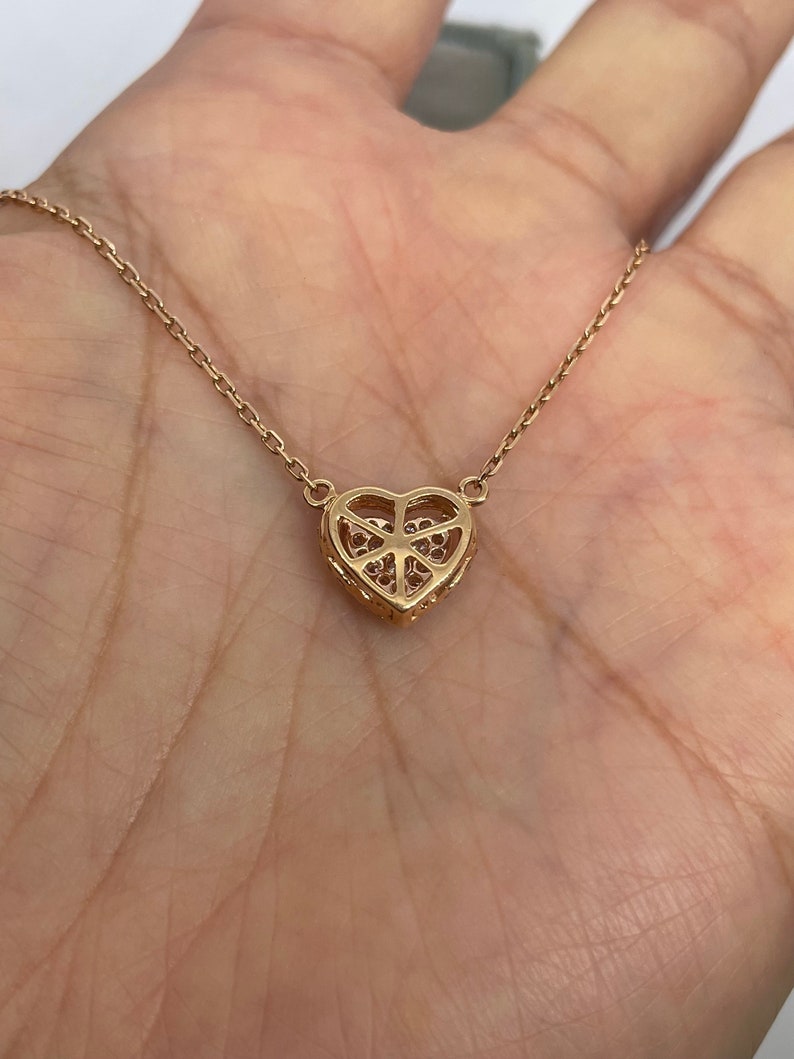 Puede incluir: Un collar de oro con un colgante en forma de coraz&oacute;n y una cadena delicada. El colgante est&aacute; adornado con peque&ntilde;as piedras brillantes.