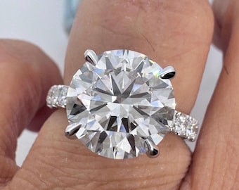 May include: A large, round, clear diamond engagement ring set in a white gold band with a pave diamond halo and band.