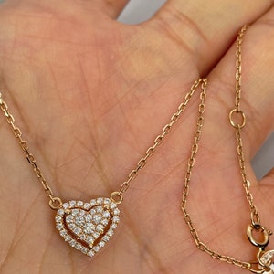 Puede incluir: Un collar de cadena de oro con un colgante en forma de coraz&oacute;n. El colgante est&aacute; cubierto de peque&ntilde;os diamantes.