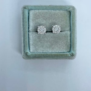 May include: A pair of round diamond earrings in a light blue velvet jewelry box.