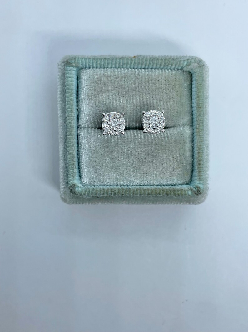 May include: A pair of round diamond earrings in a light blue velvet jewelry box.