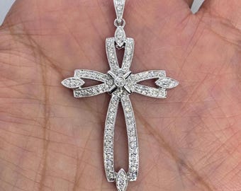 May include: A silver cross pendant with a delicate design, featuring a central diamond and smaller diamonds set around the edges.