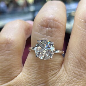 Puede incluir: Un anillo de plata con un gran diamante redondo y transparente.
