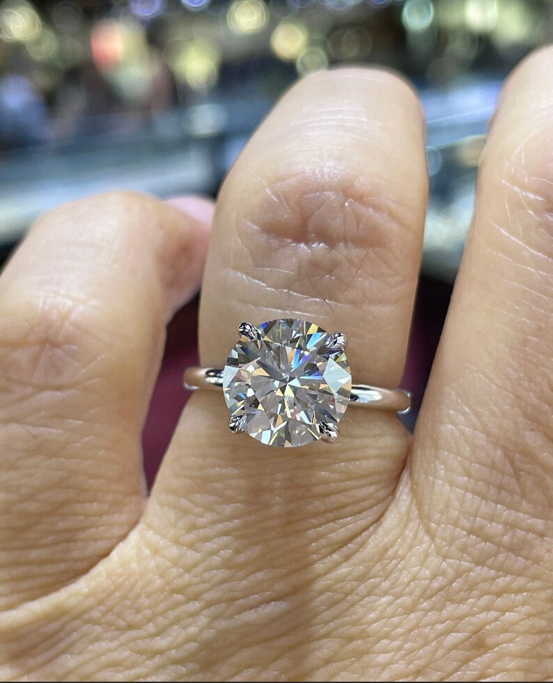 Puede incluir: Un anillo de plata con un gran diamante redondo y transparente.