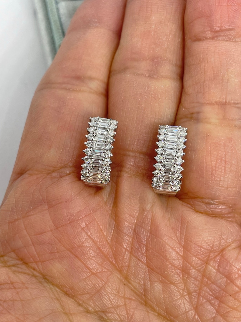May include: A pair of silver hoop earrings with a row of baguette-cut diamonds on each hoop.