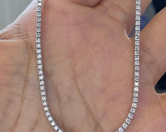 May include: A silver tennis chain necklace with small, clear diamonds.