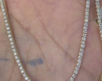 May include: A gold chain necklace with small, clear stones set in a pave setting.