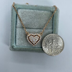 Puede incluir: Un collar de cadena de oro con un colgante en forma de coraz&oacute;n engastado con peque&ntilde;os diamantes. El colgante es aproximadamente del tama&ntilde;o de una moneda de diez c&eacute;ntimos.