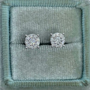 May include: A pair of silver stud earrings with a round cluster of small diamonds in a velvet box.
