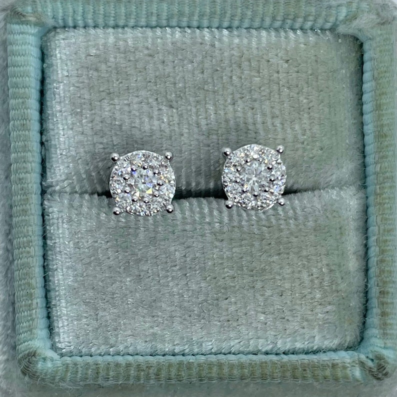 May include: A pair of silver stud earrings with a round cluster of small diamonds in a velvet box.
