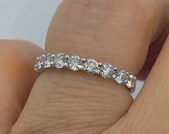 May include: A silver band with a row of round, clear gemstones.