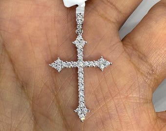 May include: A silver cross pendant with a diamond-like gemstone design. The cross features a vertical bar and a horizontal bar, with gemstones set along the bars and at the ends. The pendant is attached to a silver bail.