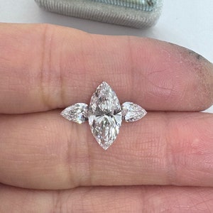 May include: A three-stone marquise diamond engagement ring with a large center stone and two smaller side stones.
