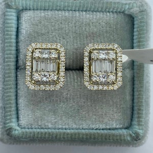 May include: A pair of gold earrings with a square shape and a halo of small diamonds surrounding a larger center diamond. The center diamond is surrounded by a row of baguette diamonds.