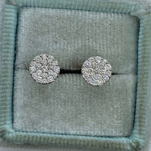 May include: A pair of silver stud earrings with a round design featuring a cluster of small, clear diamonds.