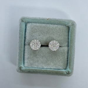 May include: A pair of round diamond stud earrings in a light blue velvet jewelry box.