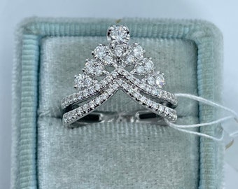 May include: A silver ring with a crown design set with small diamonds. The ring is in a blue velvet ring box.