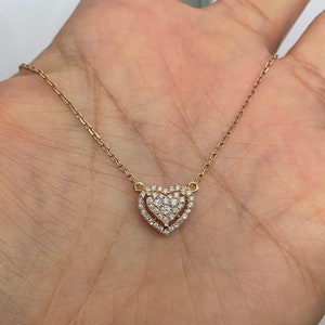 Puede incluir: Un collar de cadena de oro con un colgante en forma de coraz&oacute;n engastado con peque&ntilde;os diamantes.