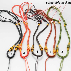 May include: Five adjustable necklace cords in black, red, brown, green, and orange. Each cord has a yellow and gold bead at the end. The cords are labeled 1 through 5.