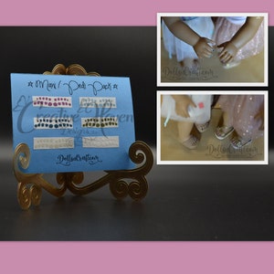 Puede incluir: Una tarjeta azul con el texto "*mani / pedi pack*" y "Creative Haven Designs" en ella. La tarjeta muestra cuatro filas de pegatinas para u&ntilde;as con diferentes dise&ntilde;os. La tarjeta est&aacute; en un soporte de metal dorado.