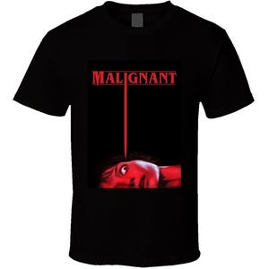 Puede incluir: Camiseta negra con un gráfico rojo de la película "Malignant". El diseño presenta el título en letras mayúsculas rojas y una imagen estilizada del rostro de una persona con un haz de luz rojo.