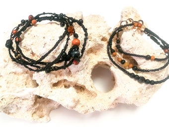 Conjunto formado por pulseras de envoltura  en diferentes estilos, una de hilo de cuero trenzado y la otra con cuentas y piedras