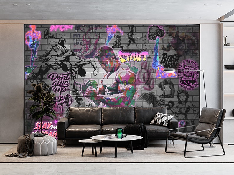 K&ouml;nnte beinhalten: Eine graue Backsteinwand mit bunten Graffiti, die motivierende S&auml;tze wie "Gib nicht auf", "Beast Mode" und "Start" zeigen. Die Wand ist mit Bildern von Menschen beim Sport verziert, darunter ein Mann, der Gewichte hebt. Die Wand befindet sich in einem Wohnzimmer mit einem schwarzen Ledersofa, einem schwarzen Ledersessel und einem Couchtisch.