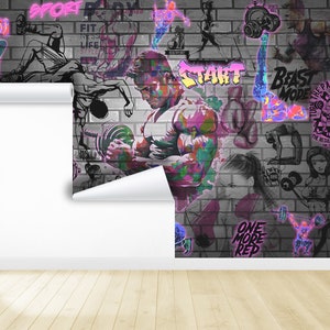 K&ouml;nnte beinhalten: Ein farbenfrohes Graffiti-Wandbild auf einer Backsteinmauer mit den Worten "Sport Body", "Fit in Life Style", "Beast Mode", "Turn the Pain into Power", "Start", "One More Rep" und "Be Patient the Results Will Speak for Themselves".