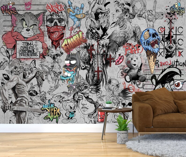 K&ouml;nnte beinhalten: Ein graues und wei&szlig;es Wandbild mit einer Vielzahl von bunten Graffiti-Kunst, darunter eine Comic-Katze, ein Sch&auml;del, ein Comic-Elefant und ein Comic-Eiswaffel. Der Text "TOM 52H416 POSSESSING STOLEN GOODS" ist an der Wand sichtbar.