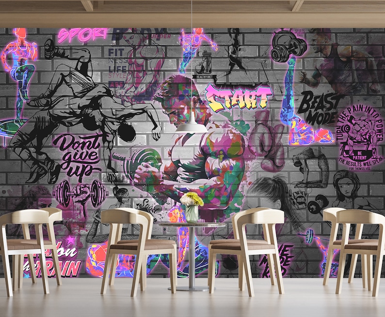 K&ouml;nnte beinhalten: Ein farbenfrohes Graffiti-Wandbild mit einem Hintergrund aus Ziegelmauer. Das Wandbild zeigt Bilder von Menschen, die trainieren, Gewichte heben und motivierende Zitate. Der Text im Wandbild beinhaltet "Sport", "Fit", "Gib nicht auf", "Beast Mode", "Verwandle den Schmerz in Kraft" und "Start".