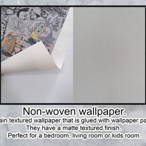 Op de afbeelding: Een close-up van een witte, niet-geweven behang met een textuur. Het behang is gedeeltelijk teruggetrokken om een kleurrijk cartoonontwerp te onthullen. De tekst "Niet-geweven behang" is onder de afbeelding gedrukt.