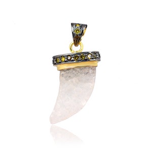 May include: A white quartz tooth pendant with a gold and black bezel set with small diamonds. The pendant is on a white background.