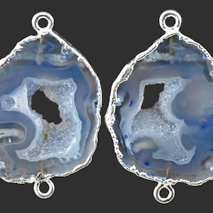 May include: Two agate slices with a blue and white pattern and a silver bail. The agate slices are shaped like a teardrop and have a hole at the top for hanging.