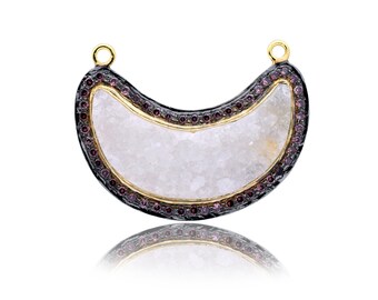 May include: A crescent moon pendant with a white, textured stone center and a black and gold rim. The rim is decorated with small, purple gemstones.