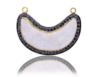 May include: A crescent moon-shaped pendant with a white quartz center and a black diamond border. The pendant is made of gold and silver.
