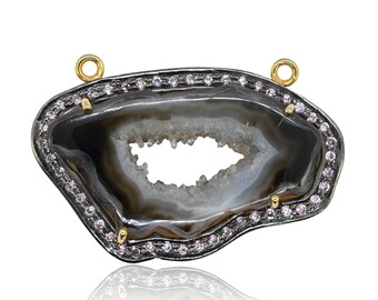 May include: A black and white agate geode pendant with a gold rim and pink gemstones around the edge. The geode has a natural crystal formation inside.
