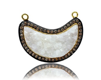 May include: A crescent moon-shaped pendant with a white crystal center and a black and gold rim. The rim is decorated with small brown gemstones.