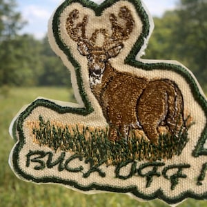 May include: A white ceramic mug with a black handle and the text "But First, Coffee" in a bold, black font. The mug is filled with a dark liquid, likely coffee, and sits on a light-colored surface.