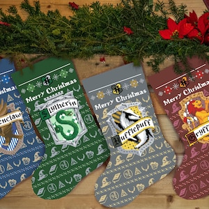 Op de afbeelding: Vier kerstsokken met een Harry Potter-thema. Elke sok is versierd met een ander wapenschild van het Hogwarts-huis: Griffoendor, Zwadderich, Huffelpuf en Ravenklauw. De sokken zijn rood, groen, grijs en blauw, en elk heeft de tekst "Merry Christmas" erop gedrukt.