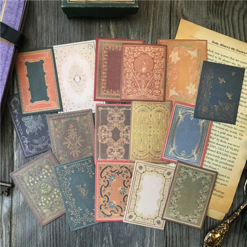 May include: A set of 14 vintage-style decorative paper stickers with ornate borders and patterns. The stickers feature a variety of colors, including gold, brown, green, and blue. The stickers are perfect for adding a touch of vintage charm to journals, planners, and other craft projects.