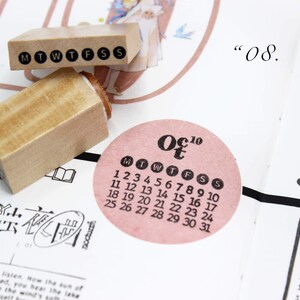 Puede incluir: Sellos de madera con los d&iacute;as de la semana y un calendario de octubre de 2010. El calendario est&aacute; en una pegatina circular rosa. Los sellos est&aacute;n en una p&aacute;gina con texto japon&eacute;s y el n&uacute;mero "08."