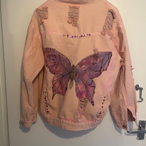 Roze noodlijdend spijkerjack op maat met handgeschilderde vlinder en versieringen