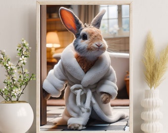 Op de afbeelding: Een bruin en grijs konijn met een witte badjas staat in een badkamer met een wit bad op de achtergrond. Het konijn kijkt naar de camera.