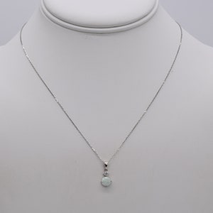 May include: A silver chain necklace with a round opal pendant accented with a small clear stone.