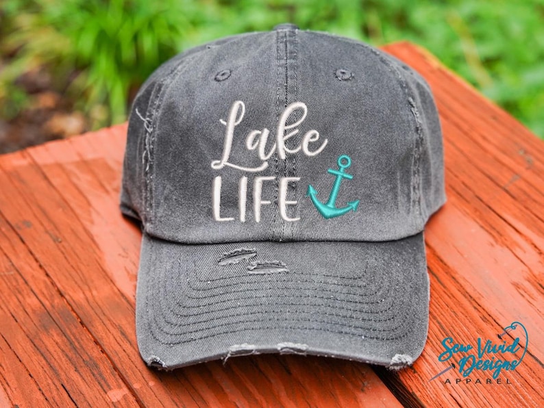 May include: A gray distressed baseball cap with the text "Lake Life" embroidered in white and a turquoise anchor embroidered on the front.