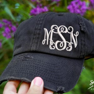 May include: A black distressed baseball cap with a white embroidered monogram "MSN".