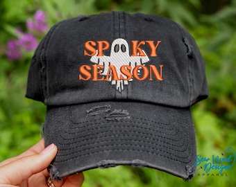 May include: Black distressed baseball cap with orange embroidered text that reads "Spooky Season" and a white ghost graphic.