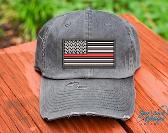 May include: A gray distressed baseball cap with a thin red line American flag patch. The patch has white stars and stripes with a red stripe across the middle.