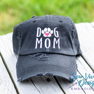 Pode incluir: Um bon&eacute; de beisebol preto desgastado com bordado branco que diz "Dog Mom" com um cora&ccedil;&atilde;o vermelho dentro de uma pegada de pata.